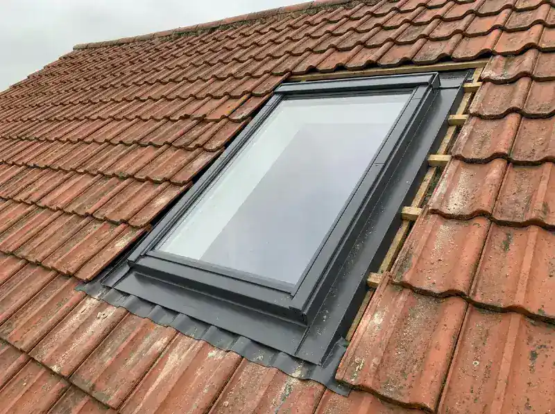 Nieuw dakraam in een pannendak geplaatst met de gootstukken rond het kader zichtbaar