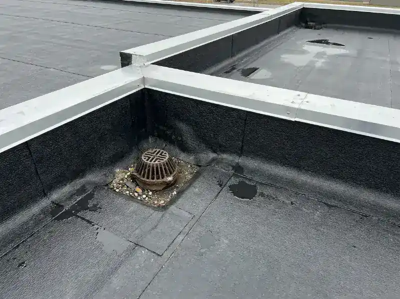 Plat dak bedekt met een zwarte epdm folie, aluminium randprofiel en een dakslokker